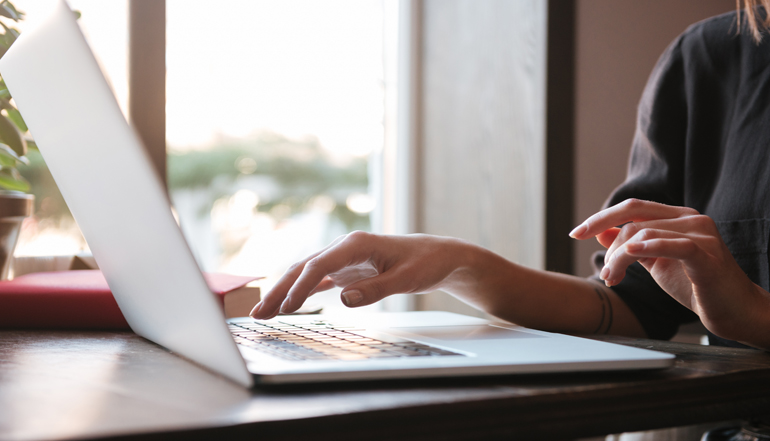 Cropped image of young woman using laptop computer.