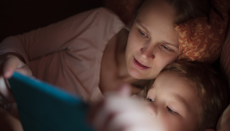 Mother and son with pad in bed at night